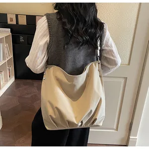 Detail van de verstelbare riem en metalen klinknagels op een beige grote shopper tas