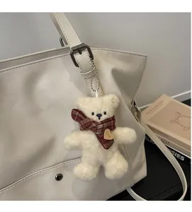 Close-up of a plush bear charm with a red plaid scarf on a tote bag detail