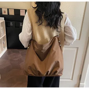 Macro-opname van bruine canvas shopper met zilveren klinknagels gedragen door model