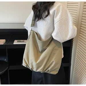 Detail van kaki canvas hobo tas met metalen klinknagels aan de riem en getextureerde stof
