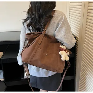Close-up of vintage brown suede tote bag with metal buckle and cute white bear charm