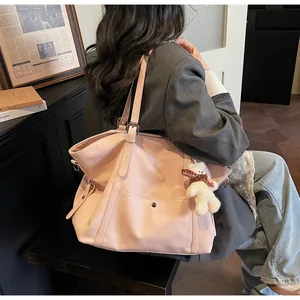 Detail of pink large tote bag with bear charm and metallic buckle on shoulder strap