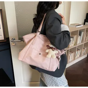 Pale pink large tote bag with cute bear charm shown worn on shoulder by a model