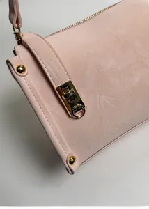 Dettaglio della chiusura in metallo dorato su borsa in pelle rosa chiaro