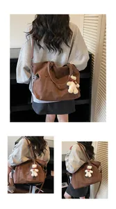 Detailed back view of a vintage dark brown tote bag with a plush bear charm on model