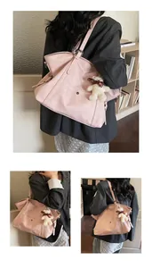 Detail view of pink large-capacity tote bag with cute plush bear charm on shoulder