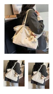 Detail of cream white tote bag with silver buckle and cute plaid scarf bear charm