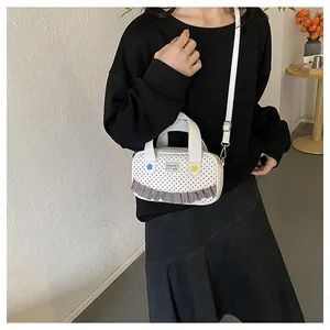 Polka dot crossbody bag featuring floral accents and check ruffle trim on a model