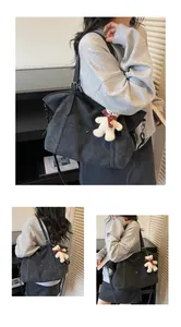 Detail of a black large-capacity tote bag with matte texture and plush bear pendant