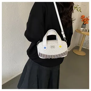 Close-up of a white polka dot crossbody bag with plaid ruffle trim worn by a model