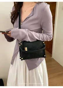 Modella che indossa una borsa a tracolla vintage in pelle opaca nera con dettagli dorati