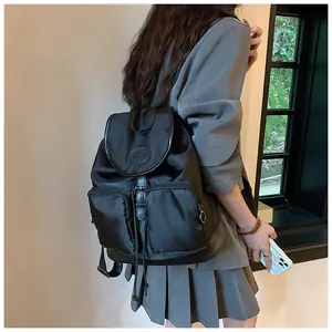Detail of black nylon backpack featuring flap buckle closure and front zip pockets