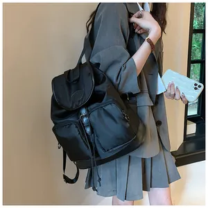 Detail of a black nylon backpack featuring a leather-trimmed flap and spacious pockets