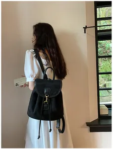 Dettaglio dello zaino in velluto nero con coulisse, ganci dorati e design minimalista