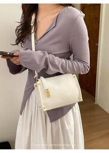 Modella che indossa una borsa a tracolla plissettata color crema con dettagli dorati