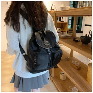 Lifestyle shot of a black Oxford nylon backpack featuring drawstring and flap closure