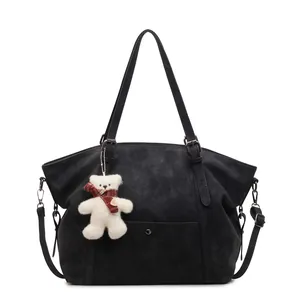 Classic black vintage tote bag with plush bear charm and adjustable shoulder strap
