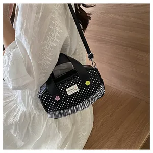 Detail shot of black polka dot bag featuring lace trim and decorative flower buttons