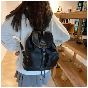 Detail of black nylon backpack featuring front zip pockets and AMAI leather logo patch