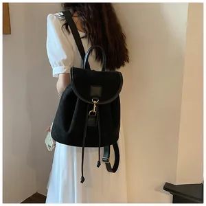 Vista posteriore di una modella con zaino in velluto nero con coulisse e fibbia dorata