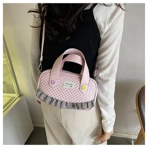 Detail of pink polka dot crossbody bag with lace edges and flower accents