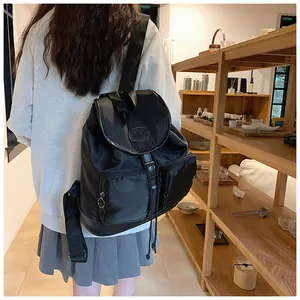 Detailed view of black nylon backpack featuring dual front pockets and AMAI logo logo