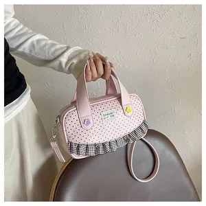 Detail of pink polka dot bag with ruffle trim and floral charms on a leather seat