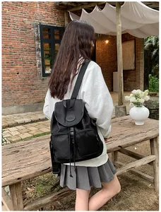 Detail of black nylon backpack with MML logo, flap cover, and dual front pockets