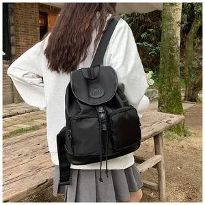 Outdoor shot of a black oxford fabric backpack with AMAI logo and front zipper pockets