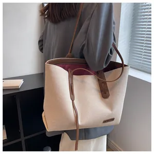 Close-up of off-white canvas tote bag with brown leather handles and wine red lining