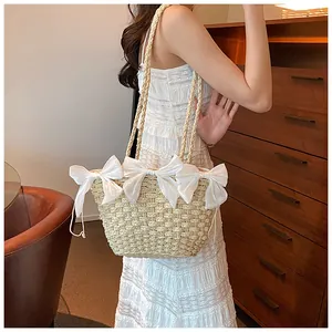 Détail du sac en paille tressé crème orné de trois élégants rubans de satin blanc