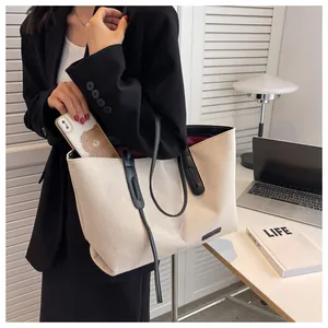 Detail of canvas tote bag featuring premium leather straps and red lining interior