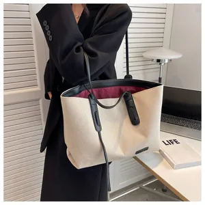 Detail of canvas tote bag with black leather trim and contrasting red inner lining