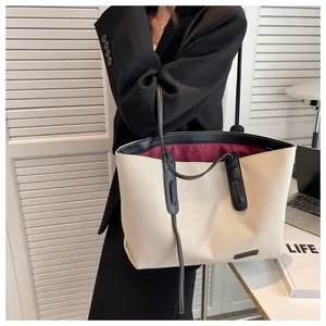 Close-up of cream canvas tote bag with black leather straps and minimalist brand label