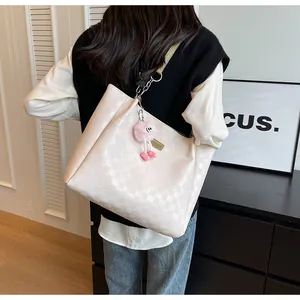 Detail of cream tote bag with checkered embossing and cute pink monster plush charm