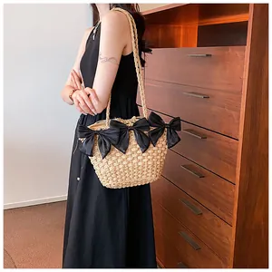 Détail d'un sac en paille tissé à la main avec de grands nœuds noirs et des bandoulières