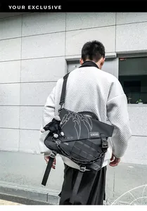 Close-up of black nylon messenger bag with metal chain detail and plush monkey charm