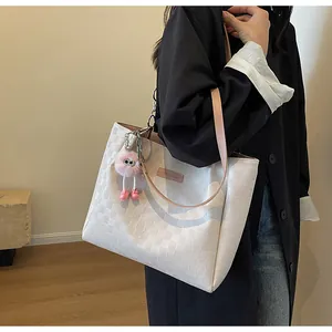 Detail of cream checkerboard tote bag with pink leather straps and plush monster charm