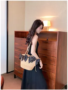 Détail d'un sac en paille d'été avec de grands nœuds en satin noir et bandoulière