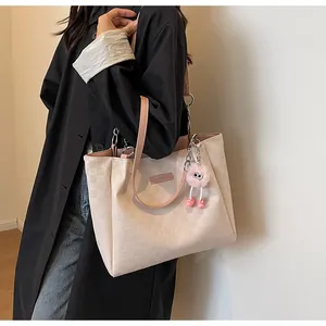 Detail of embossed lattice texture on cream tote bag with pink strap and plush charm