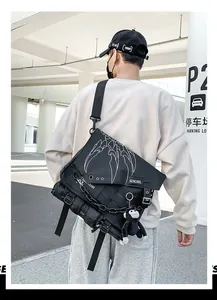 Detail of black techwear messenger bag with white claw print, chain, and monkey pendant