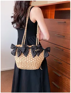 Détail du sac en paille avec nœuds noirs et texture tissée sur une tenue décontractée