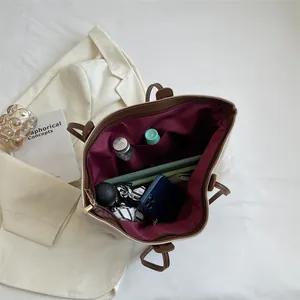 Large beige canvas tote bag with brown leather handles and spacious interior storage
