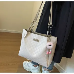Detail view of large tote bag with embossed plaid pattern and metal fashion plaque
