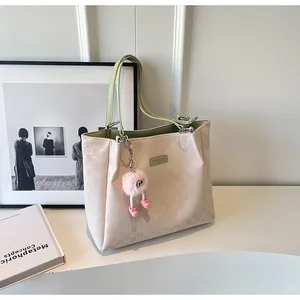 Detail of checkered embossed tote bag with green lining and pink plush eye charm accessory