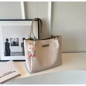 Close-up of cream-white tote bag with embossed grid pattern and cute pink plush charm