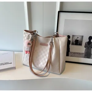 Detail of cream checkerboard tote bag featuring metal chain links and a pink plush charm