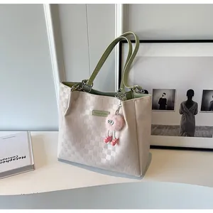 Detail of cream tote bag with avocado green handles and textured checkered pattern