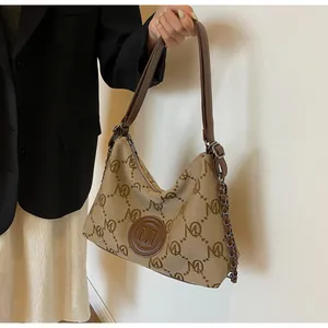 Detail of canvas tote bag showing brown monogram pattern and leather logo charm