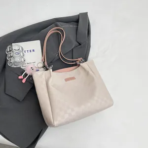 Chic beige checkered tote bag with pink handles and plush charm on a gray blazer
